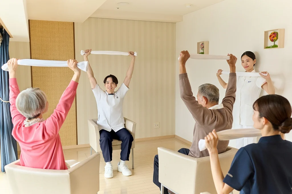 看護師と一緒に体を動かすシニアの方々